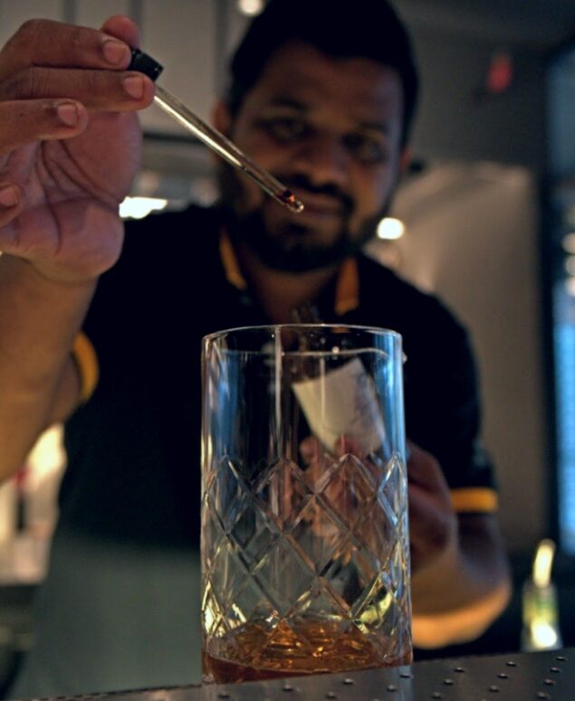 Akshar Chalwadi prépare un verre dans son bar, rākh.