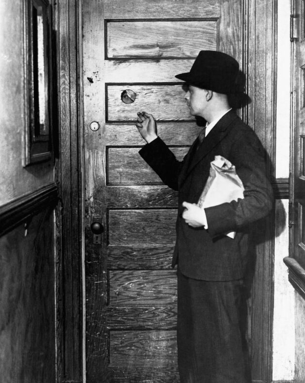 Personnes entrant dans des bars clandestins dans les années 1920, aux États-Unis, échangeant des mots de passe via un judas dans la porte.